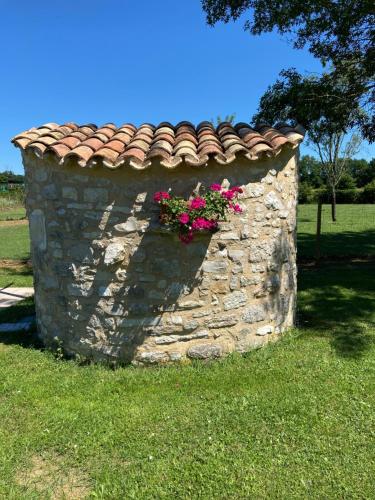 a stone wall with flowers on top of it at La petite maison dans le Quercy in Cayriech