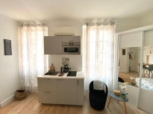 une cuisine blanche avec un évier et un micro-ondes dans l'établissement Charmant studio proche Palais des festivals - Marché Forville, à Cannes