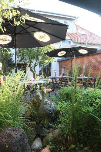 a statue of a bird in a garden under an umbrella at Rixbecker Alpen - Hotel Koch in Lippstadt