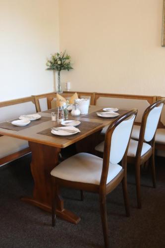 a wooden table with white chairs and a tableablish at Rixbecker Alpen - Hotel Koch in Lippstadt