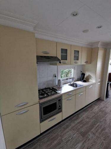 a kitchen with white cabinets and a stove top oven at Wuivend Riet gelegen op Resort Venetie in Giethoorn