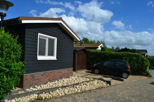 a house with a car parked in front of it at Wuivend Riet gelegen op Resort Venetie in Giethoorn