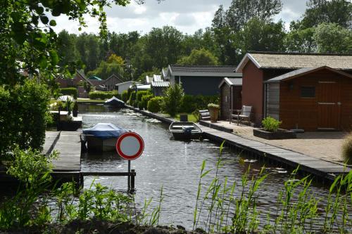 a river with boats in it next to a house at Wuivend Riet gelegen op Resort Venetie in Giethoorn