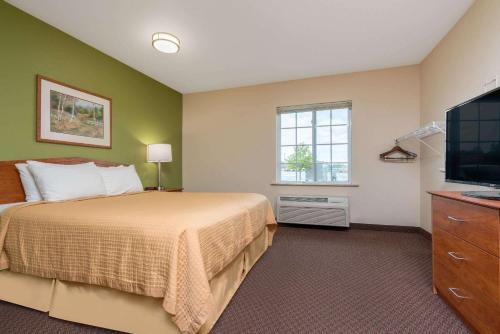 a bedroom with a bed and a flat screen tv at Days Inn & Suites by Wyndham Rochester South in Rochester