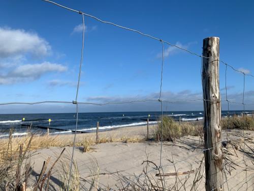 a fence on a beach with the ocean in the background at Seaside Park apartamenty prywatne z widokiem na morze in Kołobrzeg