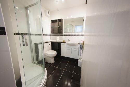 a white bathroom with a toilet and a shower at Baystays Scenic View in Swansea