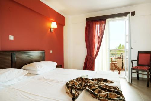 a bedroom with a white bed with a red wall at Ammos Bay in Ammoudia