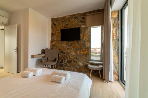 a bedroom with a bed and a stone wall at Achinos Luxury Accomodation- Pefkochori Chalkidiki in Pefkohori