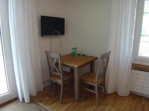 a dining room table with two chairs and a television on a wall at BnB Hopfengrün Langenthal in Langenthal