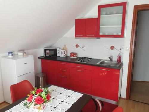 a kitchen with red cabinets and a table with flowers on it at Apartment Asgard in Drežnik Grad