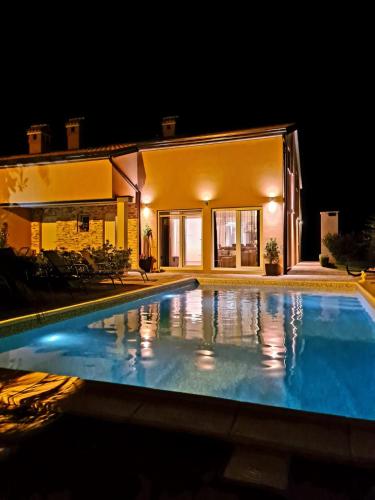 a swimming pool in front of a house at night at Villa Nemo in Poreč