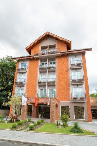 a red brick building with balconies on a street at LENA ROSA Premium Hotel in Pomerode