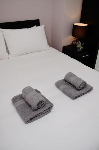 a white bed with two towels on it at 1FG Dreams Unlimited Serviced Accommodation- Staines - Heathrow in Stanwell