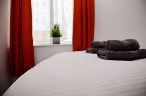 a bedroom with a white bed with red curtains at 1FG Dreams Unlimited Serviced Accommodation- Staines - Heathrow in Stanwell