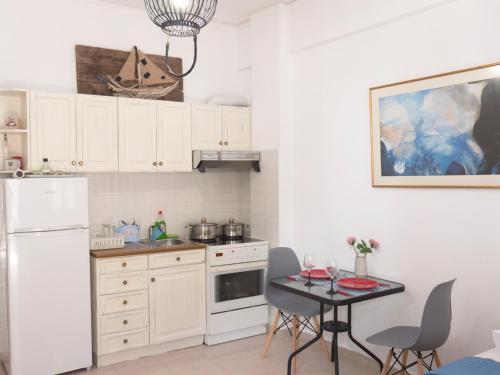a kitchen with white cabinets and a table with chairs at Nikos & Joanna's appartments in Makry Gialos