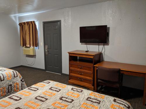 um quarto com uma cama, uma secretária e uma televisão em Budget Inn El Reno em El Reno