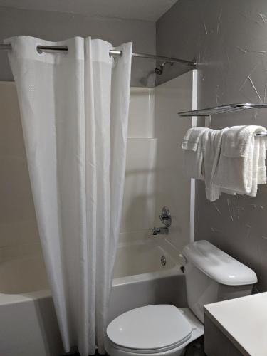 a bathroom with a white shower curtain and a toilet at Budget Inn El Reno in El Reno