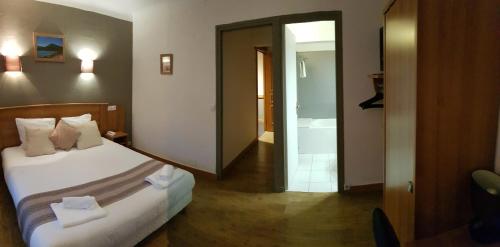 a hotel room with a bed and a bathroom at Savoy Hotel & Restaurant in Saint-Michel-de-Maurienne