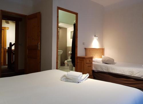 a bedroom with two beds and a bathroom with a mirror at Savoy Hotel & Restaurant in Saint-Michel-de-Maurienne