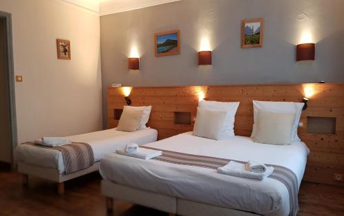 two beds in a hotel room with lights on the wall at Savoy Hotel & Restaurant in Saint-Michel-de-Maurienne