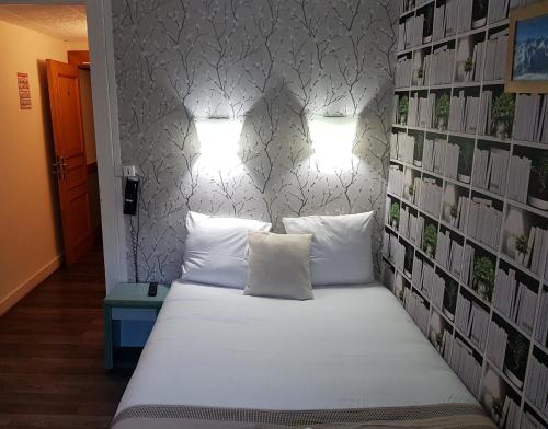 a bed in a room with two pillows and two lights at Savoy Hotel & Restaurant in Saint-Michel-de-Maurienne