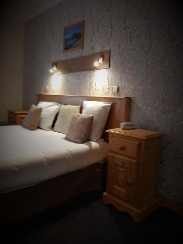 a bedroom with a bed with white pillows and a night stand at Savoy Hotel & Restaurant in Saint-Michel-de-Maurienne