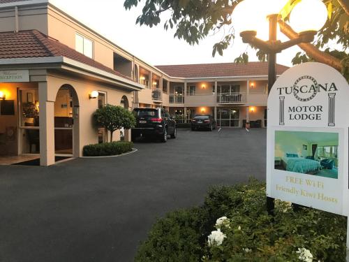 a hotel with a sign in front of a parking lot at Tuscana Motor Lodge in Christchurch