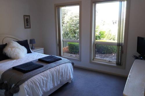 a bedroom with a bed and two windows at Victor Central Cottage Perfect Location in Victor Harbor