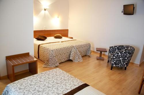 um quarto de hotel com duas camas e uma cadeira em Solar de Alqueva em Reguengos de Monsaraz