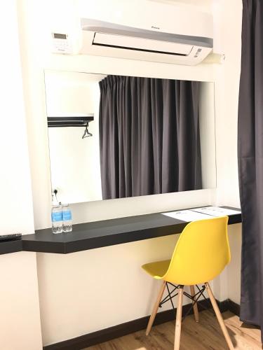 a desk with a mirror and a yellow chair at TEXAS INN in Sibu