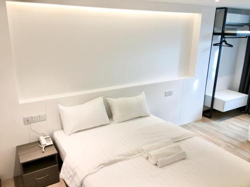 a bed with white sheets and pillows in a room at TEXAS INN in Sibu