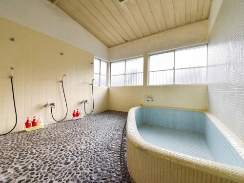 un bagno con una grande vasca in una stanza con finestre di Misaki Kanko Hotel a Muroto