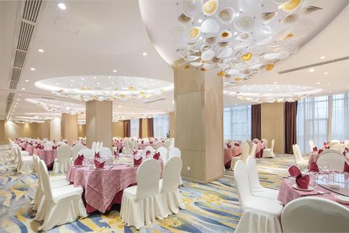 a banquet hall with white tables and chairs and a large chandelier at Perenc Hotel in Anshun