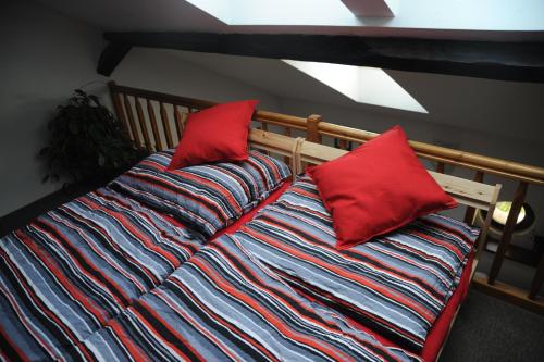 a bed with two red pillows on top of it at Apartmá v pivovaru Genius noci in Lomnice