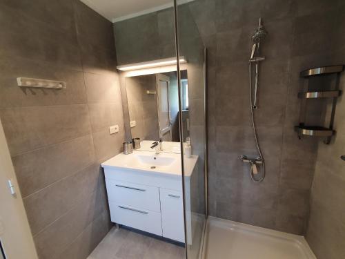 ein Bad mit einem Waschbecken und einer Dusche mit einem Spiegel in der Unterkunft Relax House Rosemary in Draga Bašćanska