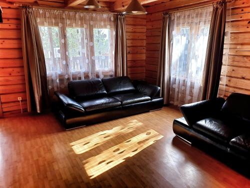 a living room with black leather furniture and windows at Sodyba Vilagio in Alanta