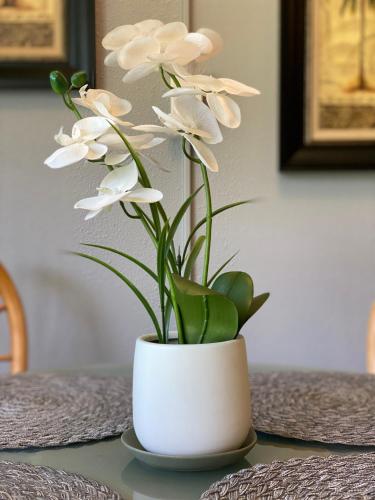 a white vase with white flowers on a table at Perfect for families and couples - Maui Sunset A-203 in Kihei