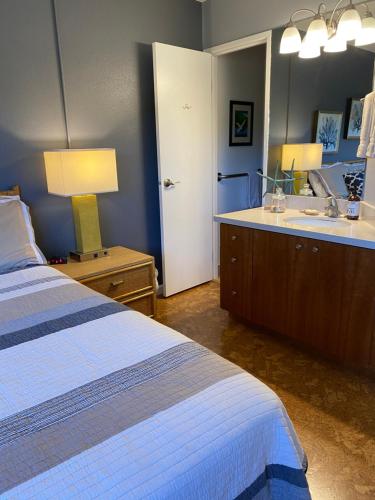 a bedroom with a bed and a bathroom with a sink at Perfect for families and couples - Maui Sunset A-203 in Kihei