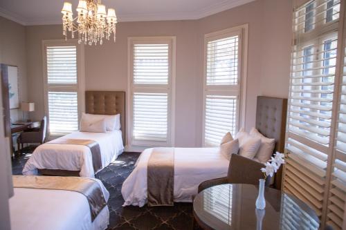 a bedroom with two beds and a table and a chandelier at Royal Hotel Randwick in Sydney