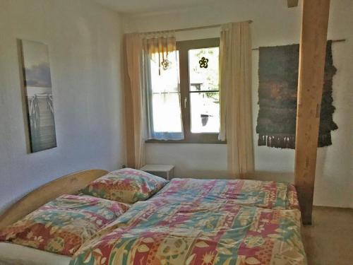 a bedroom with a bed with a comforter and a window at Ferienwohnung Christel in Wasserburg am Bodensee