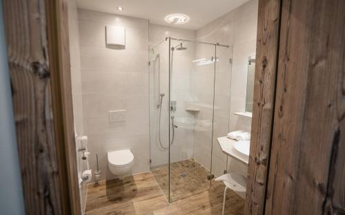 a bathroom with a shower and a toilet and a sink at Hotel Garni Isarlodge Wiesenhof in Scharnitz