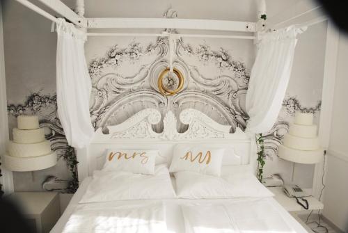 a bedroom with a white bed with a gold headboard at Hotel Hubertus in Söchau