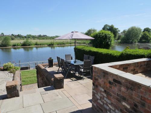 a patio with a table and an umbrella next to a river at Rondeva in Chester