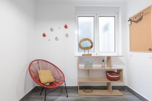 a room with a red chair and a window at Panoramic Graça Duplex with Castle and River Views by NestAtLisbon in Lisbon