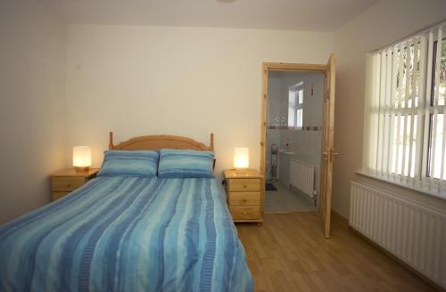 a bedroom with a bed with blue sheets and two lamps at Corralea Cottages in Belcoo