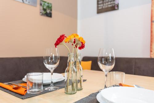 a table with wine glasses and a vase with flowers in it at Bergheim Komfort Ferienwohnungen in Walchsee