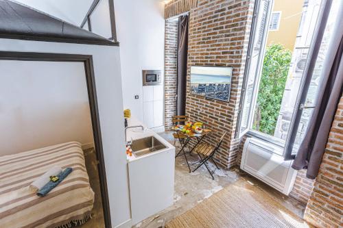 a small bedroom with a bed and a brick wall at My Casa - Place Garibaldi in Nice