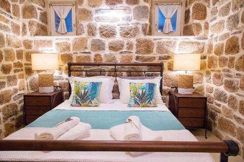 1 dormitorio con paredes de piedra y 1 cama con 2 lámparas en Lithos Residence Poros en Poros