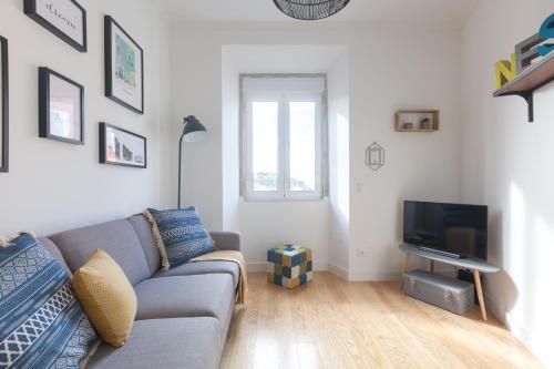 a living room with a couch and a tv at Panoramic Graça Duplex with Castle and River Views by NestAtLisbon in Lisbon