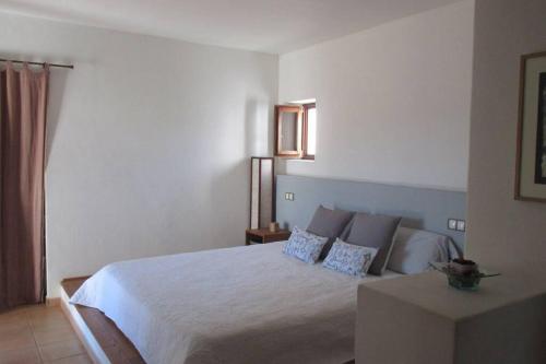 a bedroom with a large white bed with blue pillows at Sa Vinyeta in Sant Llorenç de Balafia